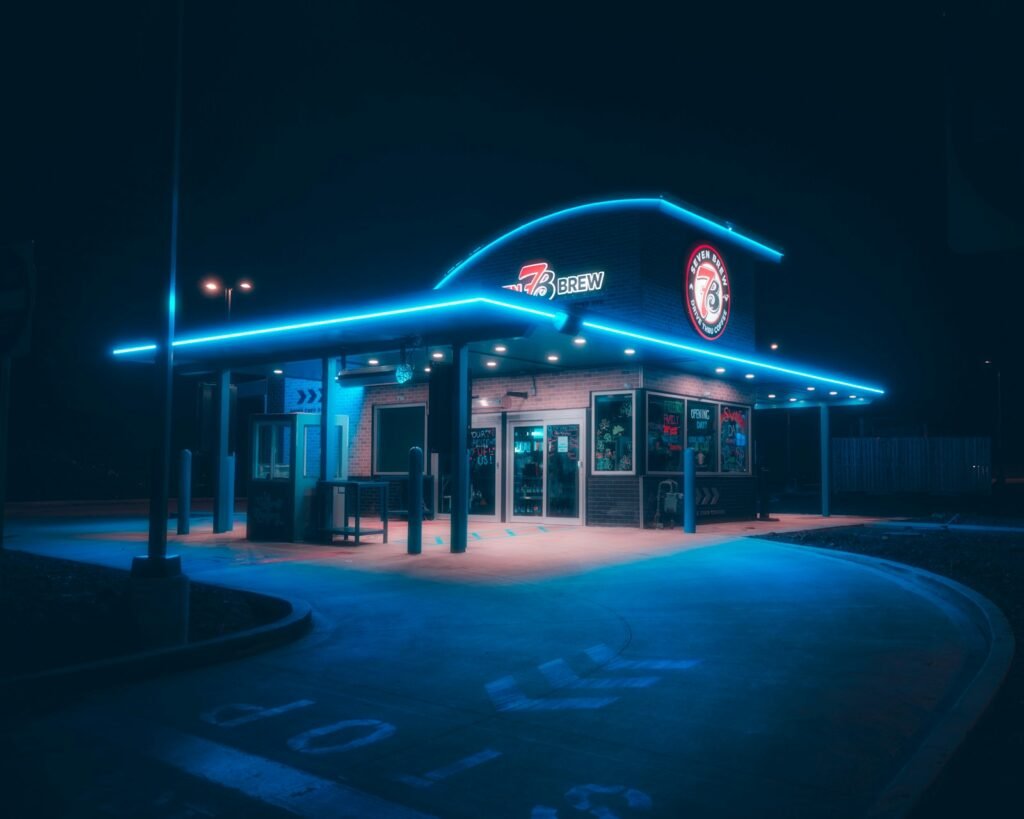 Drive-thru coffee stand lit with neon lights at night
